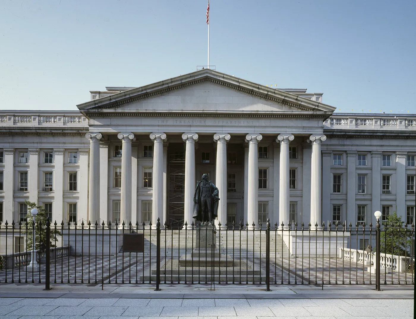 The Treasury Department building in Washington, with a statue in front of the columns.