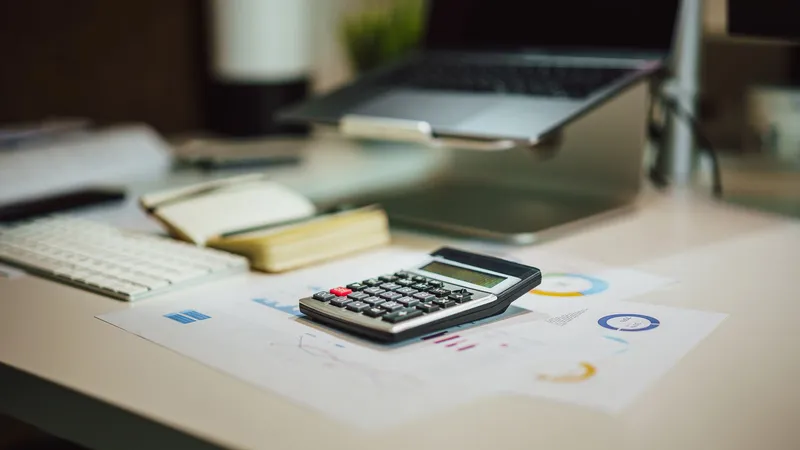 No copyright restriction A calculator resting on printed charts and papers next to a laptop.