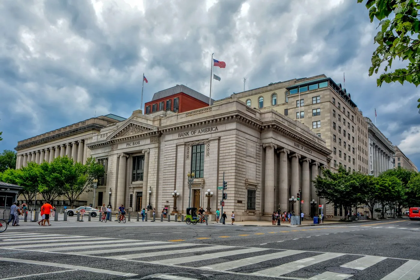No copyright restriction A stone bank building on a city corner with columns, flags, and a crosswalk.