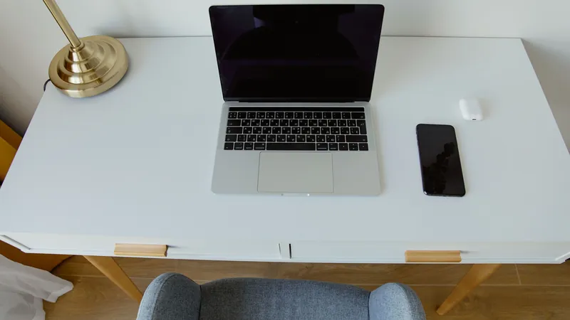 A closed laptop and a smartphone on a white desk, the kind of screen where a buy order is placed.