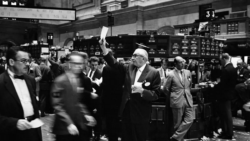 Brokers on the New York Stock Exchange floor in 1963, with a paper ticket raised at a trading post.