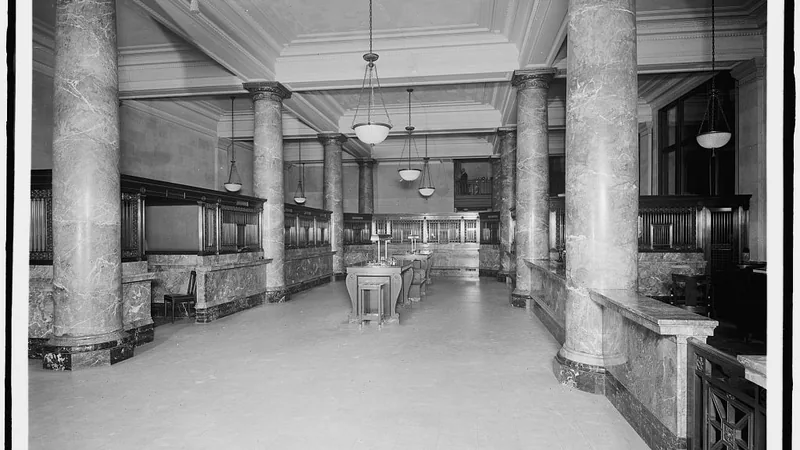 The main banking room of the Second National Bank in Boston, with marble columns and teller cages along both sides.