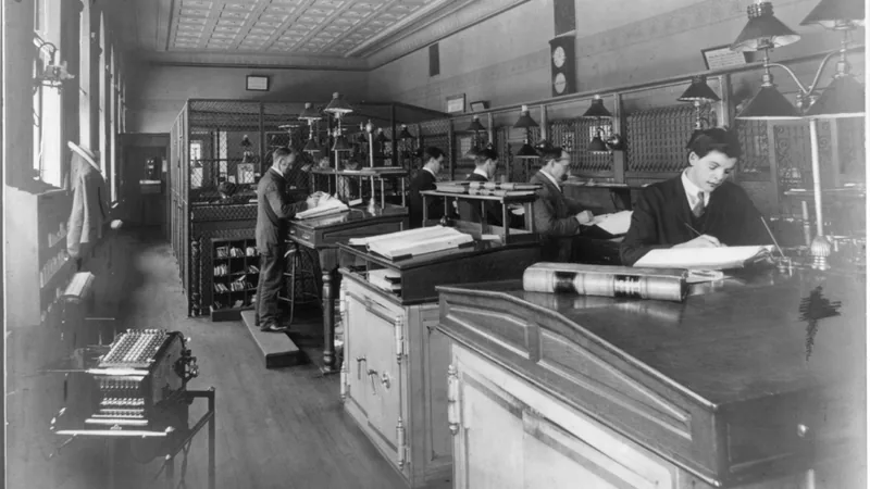 Bookkeepers writing in ledgers at the First National Bank of Somerville, New Jersey, photographed in 1908.