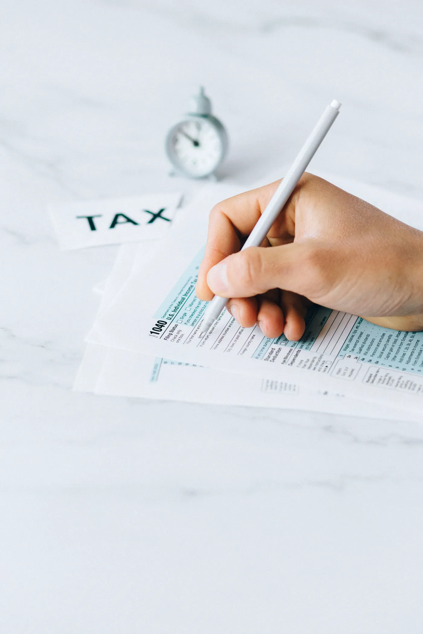 No copyright restriction A hand holding a pen over Form 1040, the U.S. individual income tax return.