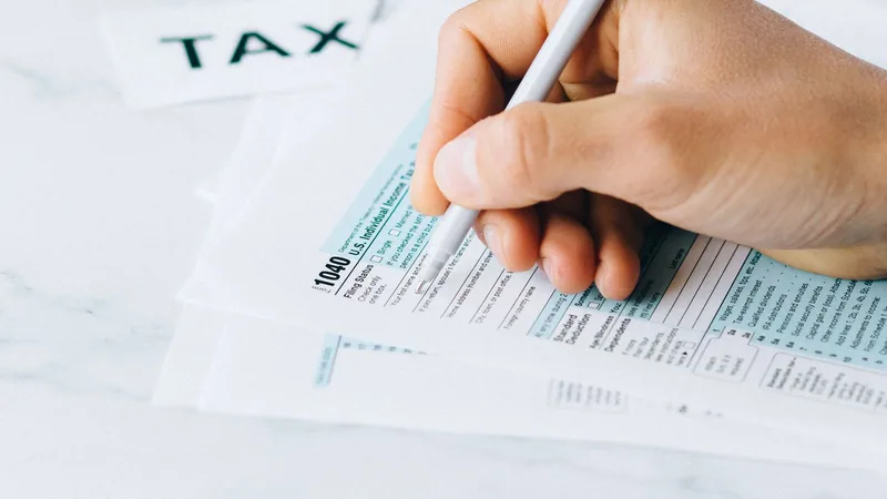 A hand filling in filing status on a paper Form 1040.